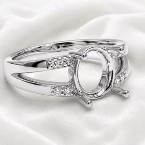 May include: A silver-toned metal ring setting featuring an oval-shaped center mount designed for a gemstone. The split shank design is accented with four small, clear, round-cut stones embedded on each side of the central prong setting.