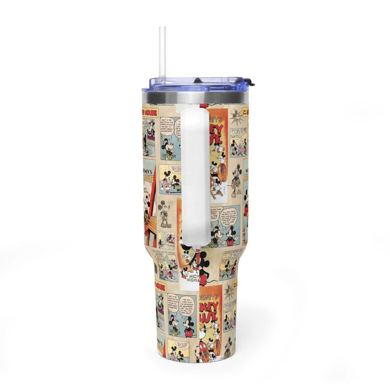 May include: A stainless steel tumbler featuring a vintage Mickey Mouse comic strip design. The tumbler has a white handle, a clear straw, and a blue lid. The design includes panels with Mickey Mouse illustrations and text.