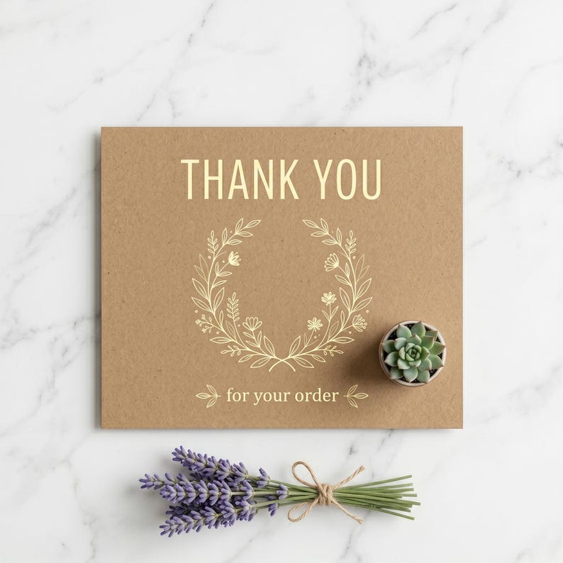 Peut inclure: Une carte en papier kraft avec les mots "THANK YOU" et "for your order" en lettres dor&eacute;es, ainsi qu'un motif de couronne florale. Une petite plante succulente dans un pot gris et un bouquet de lavande sont &eacute;galement pr&eacute;sents.