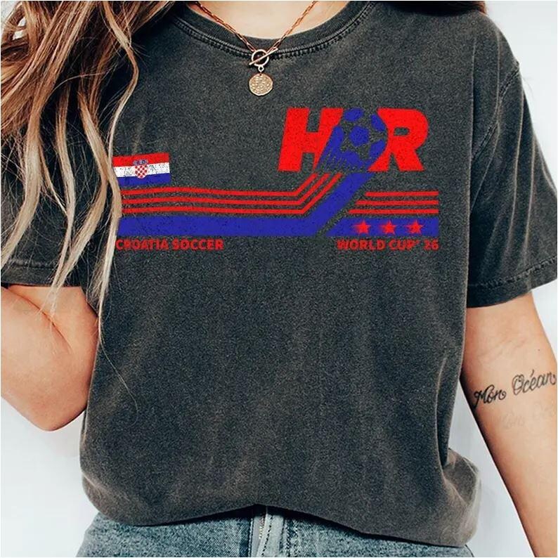 May include: Dark gray t-shirt with a Croatian soccer design. The design includes the letters "HR" in red, a Croatian flag, and the text "CROATIA SOCCER WORLD CUP '98" in red and blue. The shirt has a vintage, worn look.