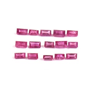 Puede incluir: Una colección de catorce piedras preciosas rosas sueltas, talladas en forma de baguette rectangular y dispuestas en tres filas horizontales. Cada piedra presenta superficies facetadas que reflejan la luz, mostrando diversas tonalidades de rosa vibrante y magenta.