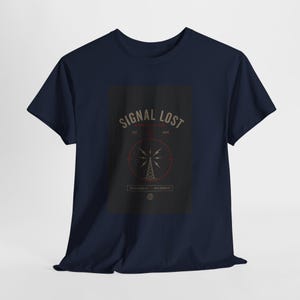 May include: Navy blue t-shirt with a graphic that reads "SIGNAL LOST" above a radio tower design. The design is in shades of gray, red, and white. The shirt is a classic crew neck style.