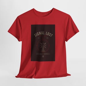 May include: A red t-shirt featuring a dark brown rectangular graphic. The graphic includes the text "SIGNAL LOST" above a stylized radio tower design. The text "DISCONNECT RECONNECT" is below the tower.