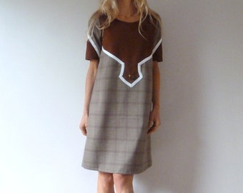 May include: A brown and white plaid dress with a brown suede yoke and white trim. The dress has short sleeves and a straight silhouette.