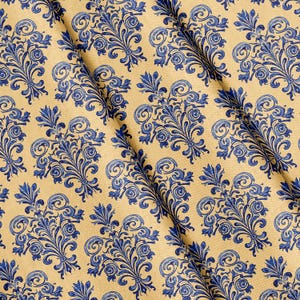 Könnte beinhalten: Ein Stoff mit einem sich wiederholenden Damastmuster in tiefem Blau auf hellbraunem Hintergrund. Das Design besteht aus symmetrischen, verzierten Blumenmotiven mit geschwungenen Schnörkeln und spitzen Blättern in einem Raster.