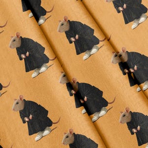May include: A mustard yellow fabric featuring a repeating pattern of light brown rats wearing black hooded robes and white sneakers. The rats are depicted in a standing position, distributed across the textured surface of the material.