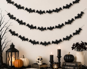 May include: Three strands of black glittery bat-shaped cutouts are hung in a scalloped pattern. Each strand features multiple bats connected by a thin string, creating a decorative garland effect suitable for hanging on a wall or mantelpiece.