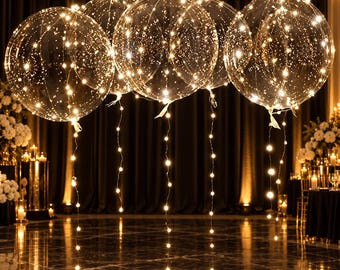 May include: Five large, transparent, spherical balloons, each illuminated by a delicate string of warm white LED lights wrapped around the exterior and trailing down from the base, creating a glowing, starry effect in a dark setting.