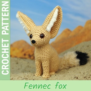 May include: A crocheted Fennec fox toy with oversized ears, a fluffy tail, and dark eyes. The fox is tan with white ear accents and a black tail tip. The text "CROCHET PATTERN" is on the left, and "Fennec fox" is at the bottom.