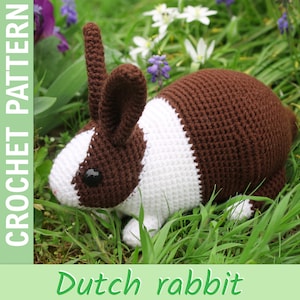 Könnte beinhalten: Ein gehäkelter Holländer-Kaninchen in Braun und Weiß, mit schwarzen Augen, liegt im grünen Gras. Das Bild enthält den Text "CROCHET PATTERN" und "Dutch rabbit".