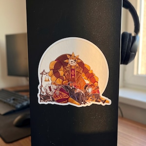 May include: A circular sticker featuring a detailed illustration of several figures. The central figure is a large, armored character in shades of brown and gold. Other figures are seated below, with intricate clothing and details. The sticker is set against a black background.