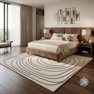 Può includere: Un tappeto rettangolare con base color crema e motivi a linee circolari concentriche marrone scuro. Il tappeto è posizionato su un pavimento in legno scuro in una camera da letto, estendendosi da sotto una struttura letto imbottita marrone.