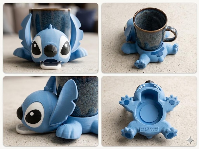 May include: A light blue 3D-printed Stitch-shaped mug holder. The holder has large black eyes, a black nose, and open mouth. The holder is designed to cradle a mug. The base of the holder has the text "ALOHA PRINTWORKS HANDCRAFTED IN HAWAII".