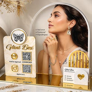 May include: A promotional display stand featuring a marble-patterned sign with the text Glint Box, a butterfly icon, QR codes, and social media handles. It includes a smaller card holder with a heart cutout and a mirror-finish base for jewelry.