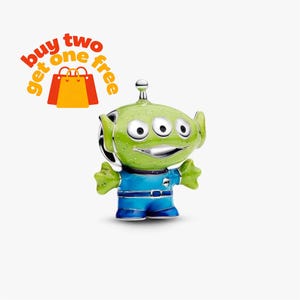 Peut inclure: Un charm argenté en forme d'extraterrestre à trois yeux avec une tête vert citron, une combinaison bleue et une petite antenne sur le dessus. Le texte "buy two get one free" apparaît en lettres orange et rouges au-dessus de deux sacs.