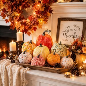 May include: A collection of fabric pumpkins in various patterns including polka dots, stripes, and floral prints, arranged in a rectangular wooden tray. The pumpkins feature stems and are displayed alongside candles, a wreath, and a sign reading Give Thanks.