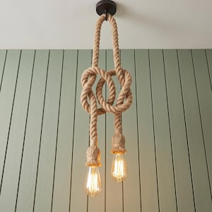 Może przedstawiać: Lampa wisząca z dwiema żarówkami w stylu Edisona zawieszonymi na grubym, skręcanym sznurze w naturalnym kolorze. Sznur jest zawiązany w ozdobny węzeł pośrodku i przymocowany do ciemnobrązowego, okrągłego mocowania sufitowego na górze.