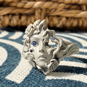 Ring med porträtt i 925 sterlingsilver med halvt ansikte, sandblästrade skulpturala blommiga smycken, ögonring med blå ädelsten, uttalandering med mörk fantasi