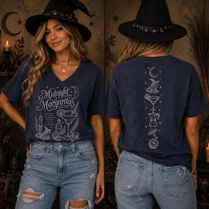 May include: A dark blue V-neck t-shirt featuring a white graphic print. The front displays the text Midnight Margaritas with illustrations of a candle, a witch hat, a potion bottle, and a margarita glass. The back shows a vertical design of a crescent moon, a witch hat, a margarita glass, a coffee pot, a mushroom, and a citrus slice.