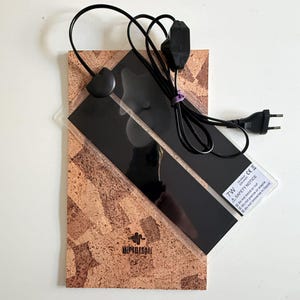 May include: A rectangular 7W heating mat with a black surface and a cork backing. The device includes a black power cord with a switch and a two-prong plug. A safety notice label is visible on the corner, and the brand name Reptilesan is printed on the cork.