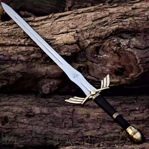 May include: A silver-colored metal sword featuring a double-edged blade with a central fuller. The hilt includes a gold-toned crossguard shaped like wings, a black cylindrical grip with decorative bands, and a rounded gold-toned pommel at the base.