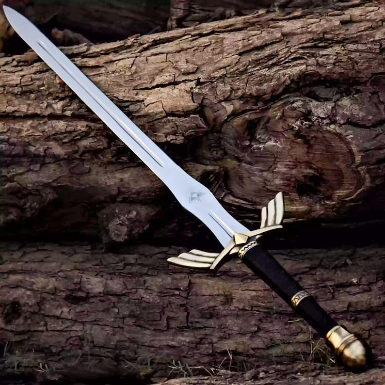May include: A silver-colored metal sword featuring a double-edged blade with a central fuller. The hilt includes a gold-toned crossguard shaped like wings, a black cylindrical grip with decorative bands, and a rounded gold-toned pommel at the base.