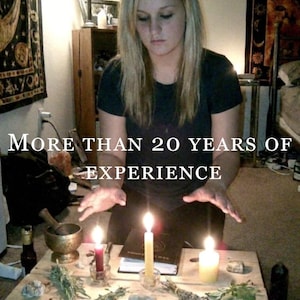 May include: A wooden table holds three lit candles, a mortar and pestle, various dried herbs, stones, and a book. The text "MORE THAN 20 YEARS OF EXPERIENCE" is overlaid on the image. The scene includes a person with blonde hair in a dark shirt.