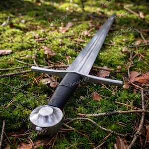 May include: A silver-colored metal sword featuring a long, double-edged blade with a central fuller, a straight crossguard, a black cord-wrapped grip, and a rounded, polished metal pommel at the base of the handle, resting on a forest floor.