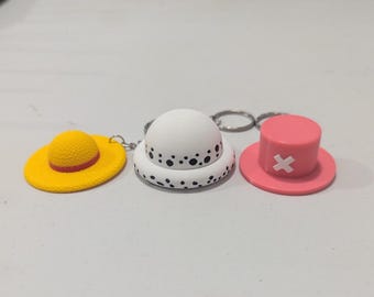 Conjunto de 3 chaveiros inspirados no anime One Piece com chapéus.