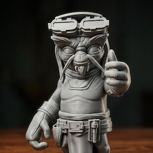 May include: A grey 3D printed figurine of a fictional creature with large ears, a goatee, and prominent eyebrows. The character wears goggles on its forehead, a belt with pouches, and is captured in a pose with one hand giving a thumbs-up gesture.