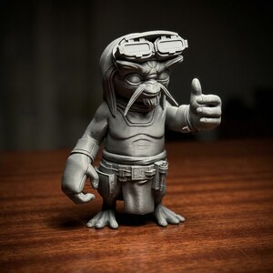 May include: A monochromatic grey figurine of a creature with large eyes, long whiskers, and a goatee. The figure wears goggles on its head, a belt with a pouch, and a loincloth. It is posed with one hand raised in a thumbs-up gesture.