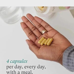 May include: Four yellow capsules are held in a person's hand. The text below the hand reads: "4 capsules per day, every day, with a meal."