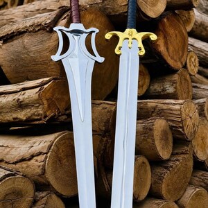 May include: Two metal swords with distinct hilts. The left sword features a silver-toned guard and a brown wrapped handle. The right sword has a gold-toned guard with a skull detail and a black wrapped handle. Both blades are long and pointed.