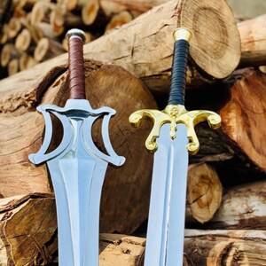 May include: Two swords with metallic blades. The left sword features a silver-toned guard and a brown leather-wrapped handle. The right sword has a gold-toned guard with a skull detail and a black leather-wrapped handle.