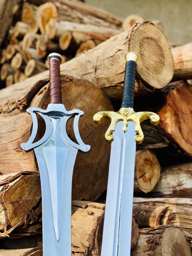 May include: Two swords with metallic blades. The left sword features a silver-toned guard and a brown leather-wrapped handle. The right sword has a gold-toned guard with a skull detail and a black leather-wrapped handle.