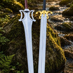 May include: Two metal swords with pointed blades. The left sword has a silver guard and a brown wrapped handle. The right sword features a gold-coloured guard with curved accents and a black wrapped handle. Both blades are polished and reflective.