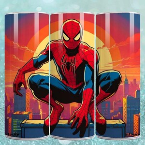 Puede incluir: Un vaso con una ilustraci&oacute;n din&aacute;mica de Spider-Man, agachado frente a un paisaje urbano. El dise&ntilde;o presenta al superh&eacute;roe con su traje rojo y azul, sobre un cielo color atardecer, al estilo c&oacute;mic.