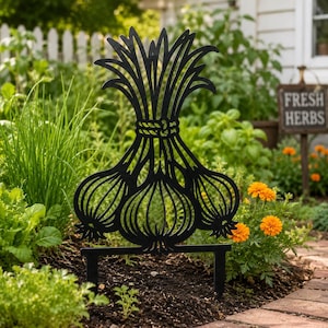 May include: A black metal garden stake featuring a silhouette design of a bundle of three garlic bulbs with long, upright green stalks tied together at the center. The decorative piece has two pointed prongs at the base for insertion into soil.