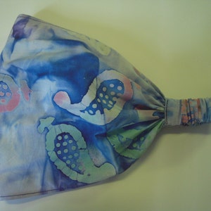 May include: A blue and white headband with a tie-dye pattern. The headband has a pink and green swirl design.