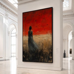 Op de afbeelding: Een groot schilderij in een lijst toont een vrouw in een vloeiende jurk, staand in een veld. De achtergrond heeft een felrode lucht met silhouetvogels. Het kunstwerk wordt getoond in een witte galerij.