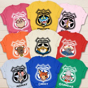 May include: A collection of colorful Zootopia-themed t-shirts. Each shirt features a different character from the movie inside a police badge design, with text like "Mommy" and "Daddy" below. The shirts are in various colors, including pink, yellow, and blue.