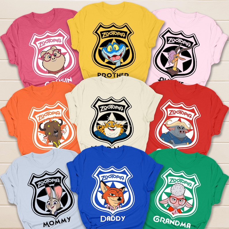 May include: A collection of colorful Zootopia-themed t-shirts. Each shirt features a different character from the movie inside a police badge design, with text like "Mommy" and "Daddy" below. The shirts are in various colors, including pink, yellow, and blue.