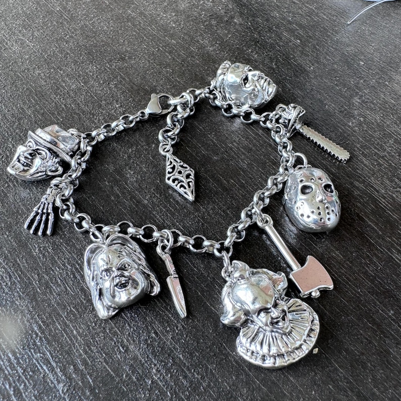 Puede incluir: Un brazalete de plata con varios dijes de personajes de pel&iacute;culas de terror, incluyendo una m&aacute;scara de hockey, un payaso y un cuchillo.