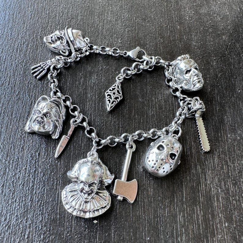 Puede incluir: Un brazalete de plata con dijes de personajes de pel&iacute;culas de terror, incluyendo Jason Voorhees, Freddy Krueger, Michael Myers y Pennywise. Los dijes est&aacute;n unidos a una cadena de plata con un cierre de langosta.