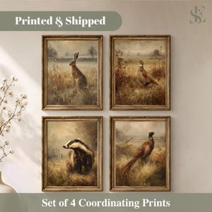 Op de afbeelding: Een set van vier rechthoekige wandkunstprints in donkerhouten lijsten. De prints tonen olieverfschilderijen van een haas, een fazant, een das en nog een fazant in een grasveld. De tekst Printed & Shipped en Set of 4 Coordinating Prints is zichtbaar.