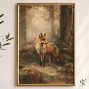 May include: A framed wall art print featuring a red fox standing in a misty, sunlit forest. The fox has orange and white fur and is positioned among dark tree trunks and green ferns. The artwork is enclosed in a thin, metallic gold frame.