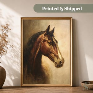 May include: A framed wall art print featuring a brown horse with a dark mane and a white blaze on its face, set against a muted beige background. The artwork is enclosed in a thin gold frame, capturing the horse in a profile view.
