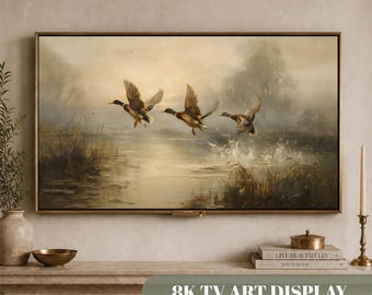 May include: A rectangular wall-mounted television displaying a digital painting of three ducks in flight over a misty, muted-toned marshland landscape. The screen features a soft, sepia-hued scene with water, reeds, and trees in the background.
