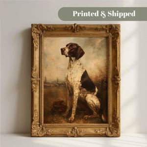 Op de afbeelding: Een ingelijst olieverfschilderij met een bruin-witte pointer hond die in een veld zit. Het kunstwerk zit in een sierlijke, antiek-stijl gouden lijst met gedetailleerde krulmotieven. De scène toont een bewolkte landschapsachtergrond.