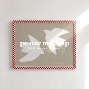 May include: A rectangular poster frame with a red and white checkered border. The print inside features two white birds flying against a solid beige background. The text "poster mockup" and "PSD Smart Object" are printed in white across the center.